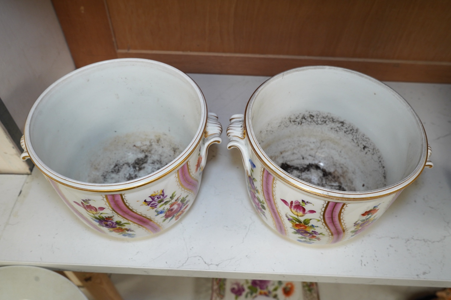 A pair of Dresden wine coolers with floral decoration, 15cm high, 18cm diameter. Condition poor to fair, cracks to the base of one.